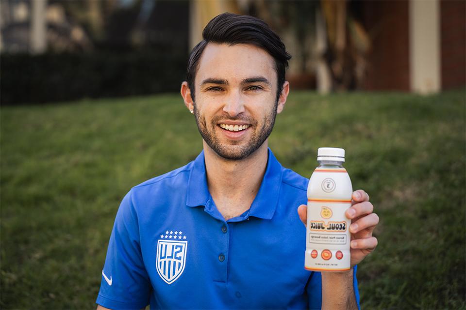 Luis Manta holds a bottle of Seoul Juice while facing the camera