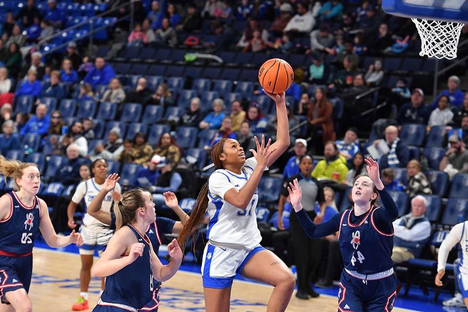 A women's basketball player shoots a basket.